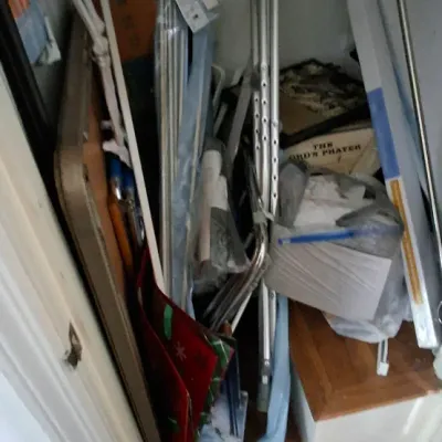 Sale Photo Thumbnail #247: A closet filled with household miscellany, including aluminum crutches, curtain rods, a folding table, framed art, and seasonal decorations.