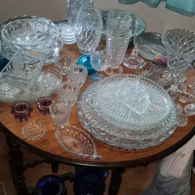 Sale Photo Thumbnail #258: Large collection of vintage pressed and cut crystal glassware, featuring various serving bowls, vases, plates, and small dishes arranged on a round wooden table.