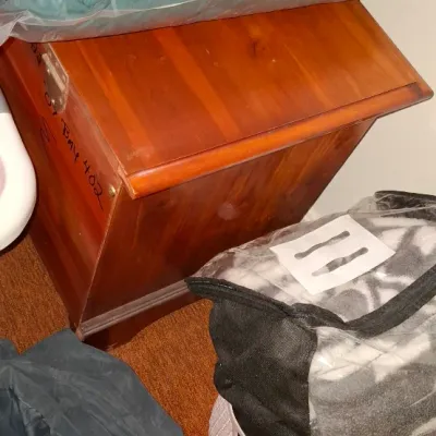 Sale Photo Thumbnail #153: Small wooden chest with a slanted lid, surrounded by packaged bedding and storage bags.