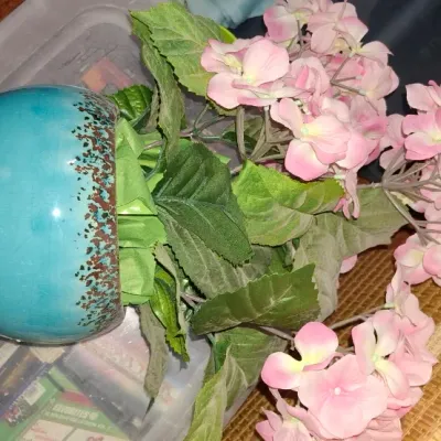 Faux pink hydrangea arrangement set inside a turquoise ceramic pot with brown speckle glaze details.