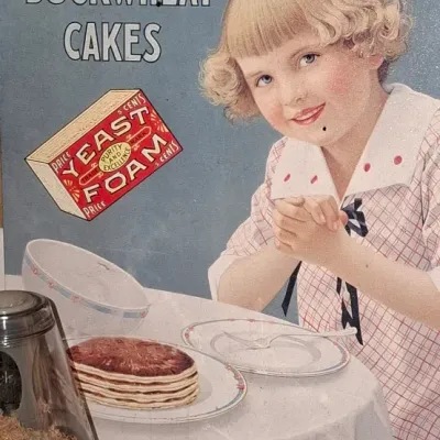 Vintage-style Yeast Foam tin advertising sign featuring a young girl at a breakfast table with a stack of buckwheat cakes.
