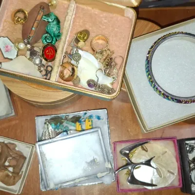 Sale Photo Thumbnail #146: Collection of vintage costume jewelry, including brooches, beaded bangles, wooden figurines, and small boxed trinkets.