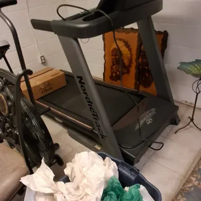 Sale Photo Thumbnail #213: NordicTrack electric treadmill with integrated display screen, set up in a basement space alongside household items.