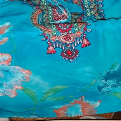 Sale Photo Thumbnail #117: Bright turquoise floral print garment featuring a ornate jeweled-style neck detail and tasseled accenting.
