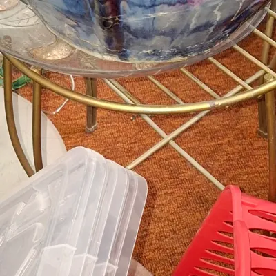 Sale Photo Thumbnail #118: Large glazed ceramic planter with a marbled blue, purple, and white pattern, resting on a brass plant stand alongside household storage items.
