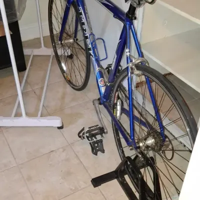 Sale Photo Thumbnail #224: Blue Trek 1200 road bicycle with straight handlebars, a padded seat, toe-clip pedals, and an included black floor parking stand.