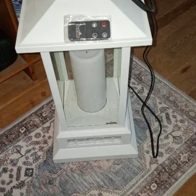 Sale Photo Thumbnail #269: Duraflame lantern-style electric heater in white, complete with a remote control resting on the lid.