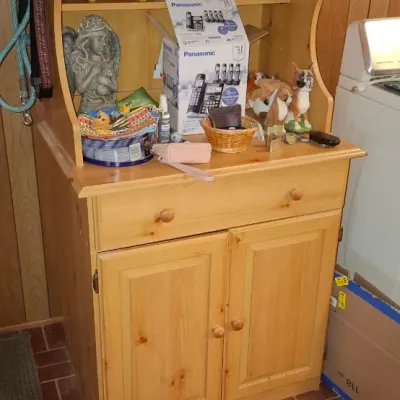 Light pine microwave hutch cabinet featuring an open upper shelf, one wide drawer, double door lower storage, and a stainless steel...