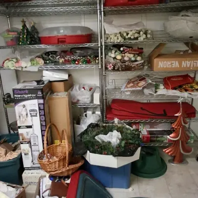 Sale Photo Thumbnail #166: Collection of holiday decorations, storage bins, artificial wreaths, floral crafts, and household items organized on wire shelving and the floor.