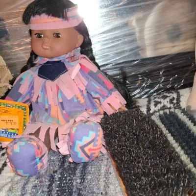Sale Photo Thumbnail #217: Collection of decorative items including two Native American style dolls, a pair of shoe brushes, and a stuffed pig figurine.