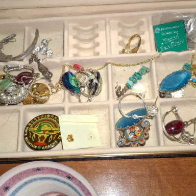 Sale Photo Thumbnail #139: Open jewelry box containing an assortment of vintage costume jewelry, including turquoise pieces, brooches, rings, and clip-on earrings.