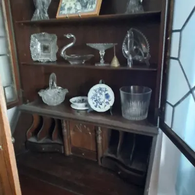 Sale Photo Thumbnail #240: Traditional mahogany secretary desk with a broken-arch pediment top, glazed cabinet doors, and cubby drawers, filled with decorative glassware and collectibles.