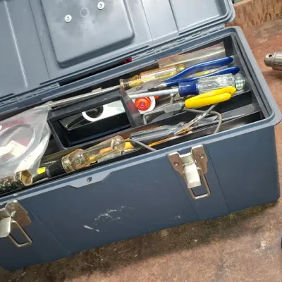 Sale Photo Thumbnail #225: Gray plastic toolbox filled with assorted hand tools, screwdrivers, and pliers, sitting next to a blue Bosch corded power drill.
