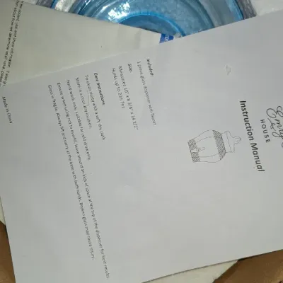 Instruction manual and original packaging for an Emryn House glass drink dispenser inside its retail box.