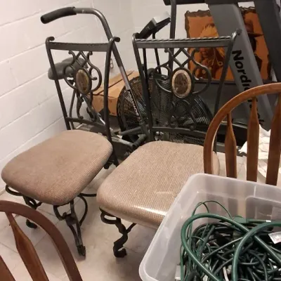 Sale Photo Thumbnail #214: Pair of wrought iron dining chairs with upholstered seats alongside exercise equipment including a NordicTrack treadmill and a stationary bike.