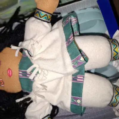 Vintage soft-sculpture Native American cloth doll, featuring yarn hair and detailed traditional-style felt and fabric attire.