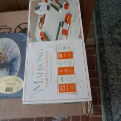 Boxed Mahjong Limited Edition game set sitting on cardboard alongside a small photo album.