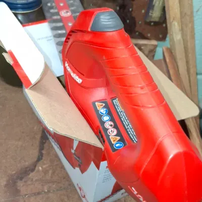 Sale Photo Thumbnail #226: Red Homelite cordless handheld power tool, resting on its original retail packaging in a workshop setting.