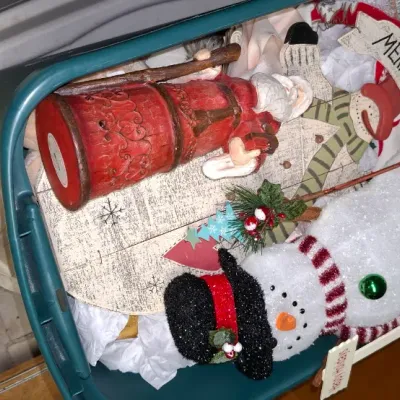 Sale Photo Thumbnail #208: Plastic storage bin filled with holiday decorations, including a lighted snowman figure, a carving-style Santa Claus, and festive wall signs.