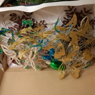 Sale Photo Thumbnail #172: Box filled with decorative Christmas ornaments, featuring glittery gold butterflies, beaded picks, and glass bulbs.