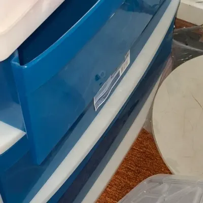 Sale Photo Thumbnail #119: Three-drawer blue and white plastic storage cart, shown next to plastic bin lids in fair condition.