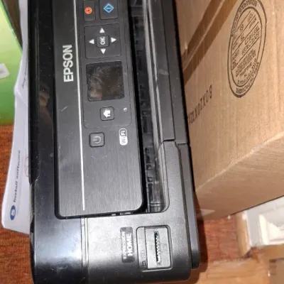 Black Epson Expression Home XP-320 all-in-one wireless printer stored inside a cardboard box.