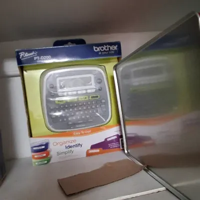 Sale Photo Thumbnail #107: Brother P-touch PT-D200 electronic label maker in original retail packaging, sitting on a shelf.