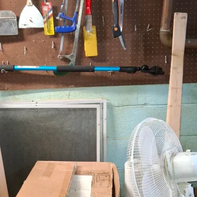 Sale Photo Thumbnail #235: Workshop items including wall-mounted pegboard hand tools, a white pedestal fan, a tower fan, and a boxed item.