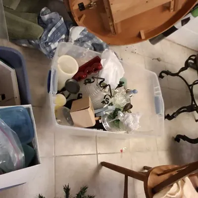 Sale Photo Thumbnail #196: Assorted household goods, including plastic storage totes with glassware, a wooden dining chair, cast iron chairs, and a round tabletop.