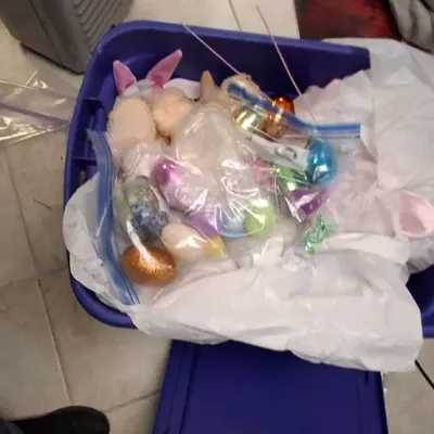 Sale Photo Thumbnail #197: Blue plastic storage tub filled with Easter decorations, including plush bunnies, plastic eggs, and holiday accessories.