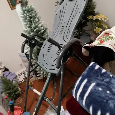 Sale Photo Thumbnail #135: Teeter inversion table with grey backrest and black metal frame, surrounded by household decor and artificial Christmas trees.