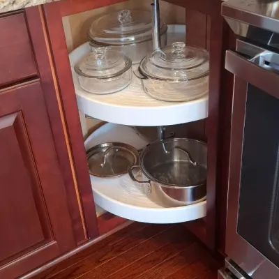 Sale Photo Thumbnail #75: Corner kitchen cabinet with a two-tier lazy Susan organizer containing modern clear glass casserole dishes and a stainless steel stockpot.