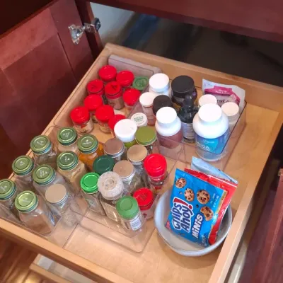 Sale Photo Thumbnail #78: Pull-out kitchen cabinet drawer organized with acrylic spice racks holding various spices, supplements, and snack packs.