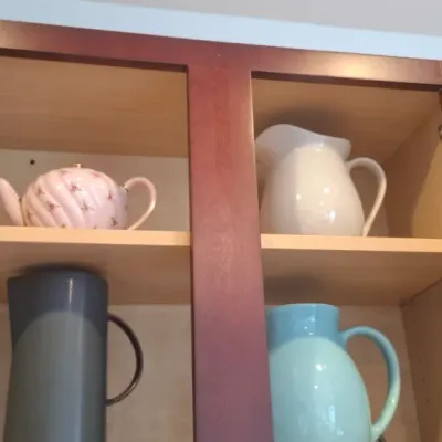 Sale Photo Thumbnail #71: Selection of ceramic teapots and pitchers, including a pink floral teapot, a white ceramic pitcher, a tall grey modern pitcher, and a two-tone blue pitcher, stored inside a wooden cabinet.