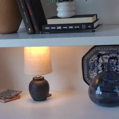 Sale Photo Thumbnail #30: White built-in shelving styled with home decor items including a small accent lamp, ceramic vases, books, and a blue and white patterned platter.