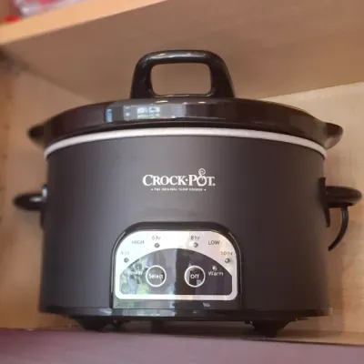 Sale Photo Thumbnail #70: Black Crock-Pot programmable slow cooker stored inside a wooden kitchen cabinet, appearing in good, gently used condition.