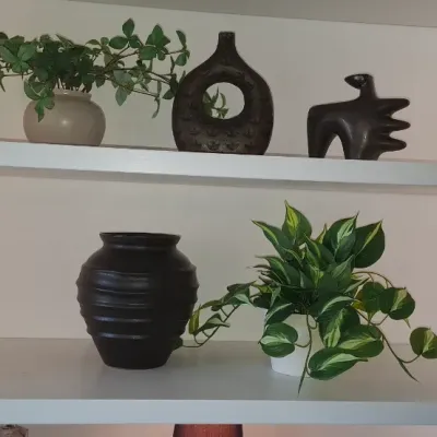 Sale Photo Thumbnail #19: Collection of decorative items on built-in white shelves, including dark ceramic vases, abstract sculptures, and potted houseplants.