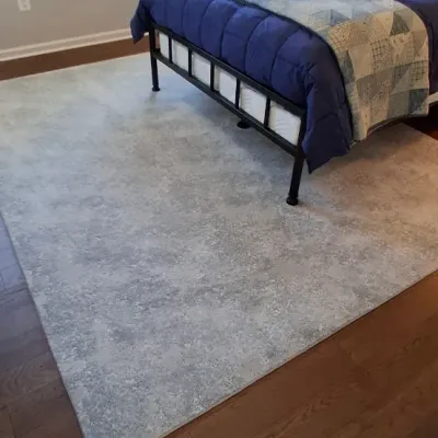 Sale Photo Thumbnail #39: Contemporary mottled light blue area rug laid on hardwood floor, underneath a black metal bed frame with blue bedding.