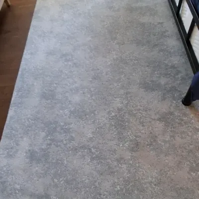 Sale Photo Thumbnail #41: Contemporary mottled grey area runner rug placed alongside a dark metal bed frame on wood flooring.