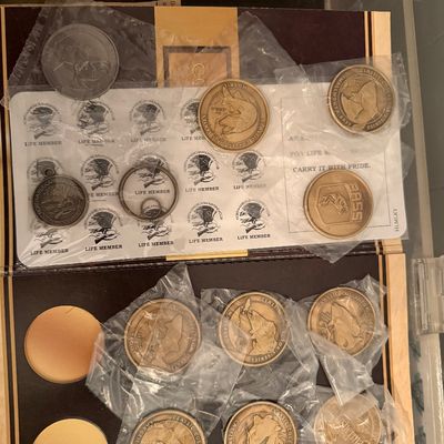 Sale Photo Thumbnail #122: Collection of North American Hunting Club and fishing-themed commemorative coins and medallions, mostly sealed in plastic sleeves.