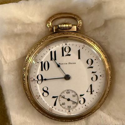 Sale Photo Thumbnail #9: Antique South Bend pocket watch with an engraved gold-filled case, white enamel dial, bold Arabic numerals, and a subsidiary seconds dial.
