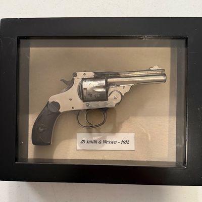 Sale Photo Thumbnail #3: Framed display case containing a top-break revolver labeled as a .38 Smith & Wesson from 1912.