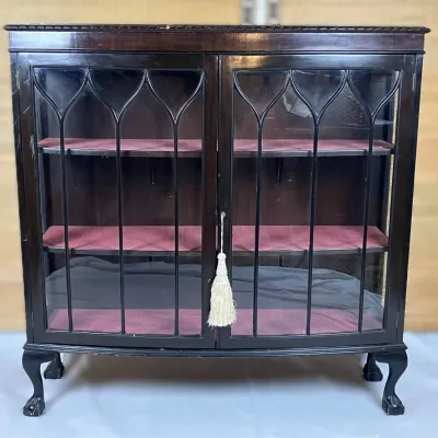 Sale Photo Thumbnail #68: Vintage dark mahogany display cabinet featuring gothic arch glass paneled doors, velvet-lined shelves, and cabriole legs with ball-and-claw feet.