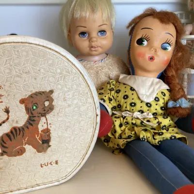 Sale Photo Thumbnail #136: Vintage mid-century cloth doll with auburn hair alongside a circular vinyl hatbox featuring a tiger illustration and several additional vintage baby dolls.