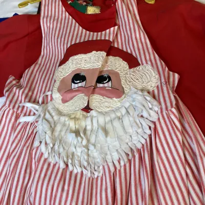 Sale Photo Thumbnail #154: Vintage red-and-white candy cane striped Christmas apron featuring a large appliquéd Santa Claus face with a textured fringe beard.