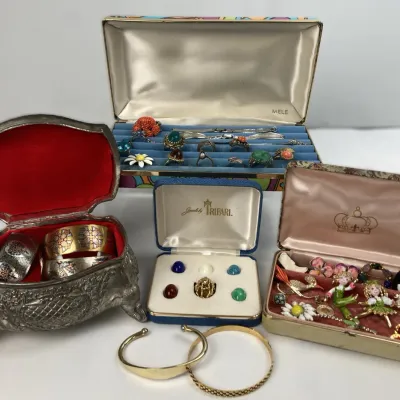 Sale Photo Thumbnail #221: Collection of vintage costume jewelry, including a red-lined metal jewelry box with cuff bracelets, a Jewels by Trifari interchangeable cabochon ring set, and a Mele ring box.