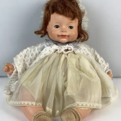 Sale Photo Thumbnail #124: Vintage Ideal 'Thumbelina' baby doll with auburn hair, wearing a lace dress, knitted cardigan sweater, bonnet, and booties, circa 1960s.