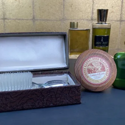 Sale Photo Thumbnail #248: Vintage men's grooming collection featuring aboxed travel brush set, Crabtree & Evelyn sandalwood shaving soap in a wooden bowl, and bottles of Polo Ralph Lauren and Jade East cologne.