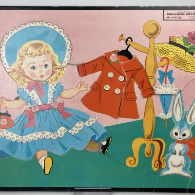 Sale Photo Thumbnail #182: Vintage 1950s Whitman frame-tray pre-school inlay puzzle featuring a dress-up doll theme with paper doll-style clothing and accessories, showing mild wear around the edges.