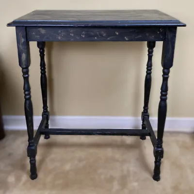 Sale Photo Thumbnail #177: Black-painted wooden side table featuring turned legs, lower stretchers, and distressing with visible gold undertones.